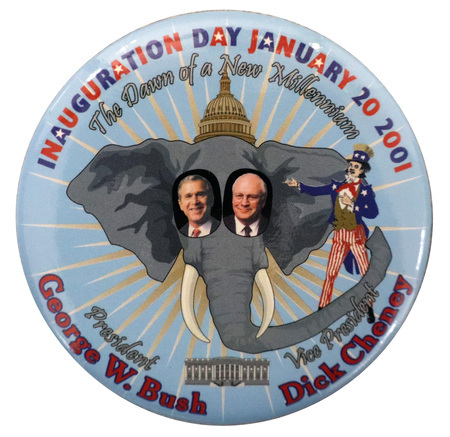 Round, blue button with a color illustration of an elephant's head topped by the US Capitol dome and accompanied by an Uncle Sam figure and the White House. In the center are color photographs of George W. Bush and Dick Cheney. Red, white, blue, and gray text reads "INAUGURATION DAY JANUARY 20 2001 The Dawn of a New Millennium President George W. Bush Vice President Dick Cheney"