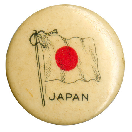 Round, white button with a color illustration of the flag of Japan, a red circle on a white field. Black text at the bottom reads "JAPAN"