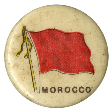 Round, white button with a color illustration of the flag of Morocco under the Alawi dynasty, solid red with no decoration. Black text at the bottom reads "MOROCCO."