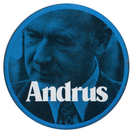 Round, blue button with a blue and black photograph of Cecil Andrus. White text reads "Andrus"