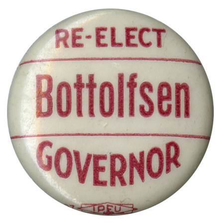 Round, white button with red text reading "RE-ELECT Bottolfsen GOVERNOR"