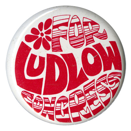 Round, white button with swirling red text reading "FOR LUDLOW CONGRESS"