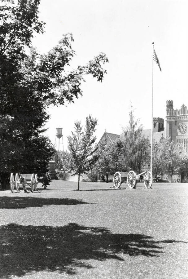 1915 photograph of cannons. Administration Building and water tower in background. [PG1_100-01]