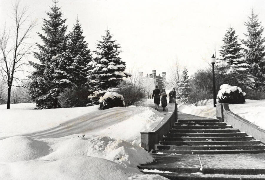 1946 photograph of the Hello Walk steps. Snow covers the scene as three students approach steps. [PG1_102-16]