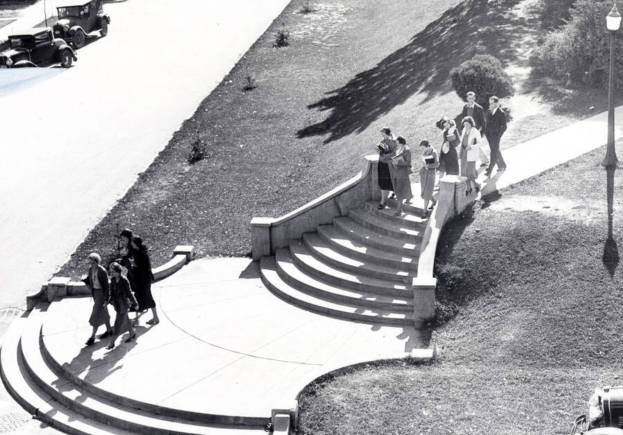 1940 photograph of the Hello Walk steps. Students on steps and automobiles in background. [PG1_102-04]