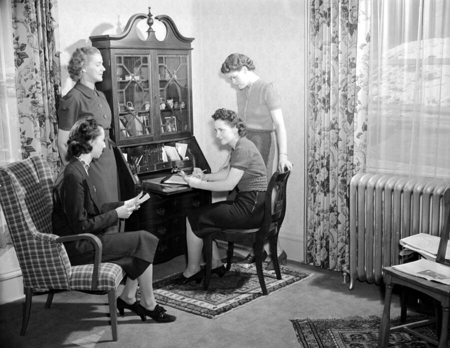 1939 photograph of the Home Management House. Women work around a desk. [PG1_106-04]
