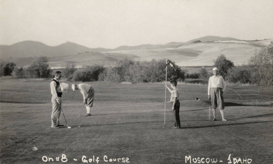 1938 photograph of the Golf Course. Three adults and a child play are shown playing golf. [PG1_110-02]