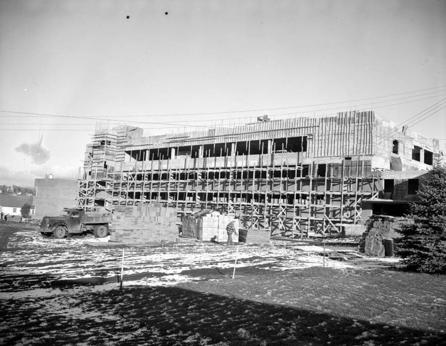 December 9, 1949 photograph of the Agricultural Science Building under construction. Automobile and construction worker in foreground. [PG1_111-20a]