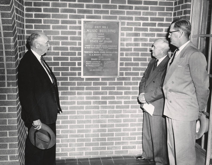 1952 photograph of men standing in front of a plaque in the Music Building. Left to right: Regent W.F. McNaughton, Governor C. A. Robins, President J.E. Buchanan. Donor: Publications Dept. [PG1_117-09]