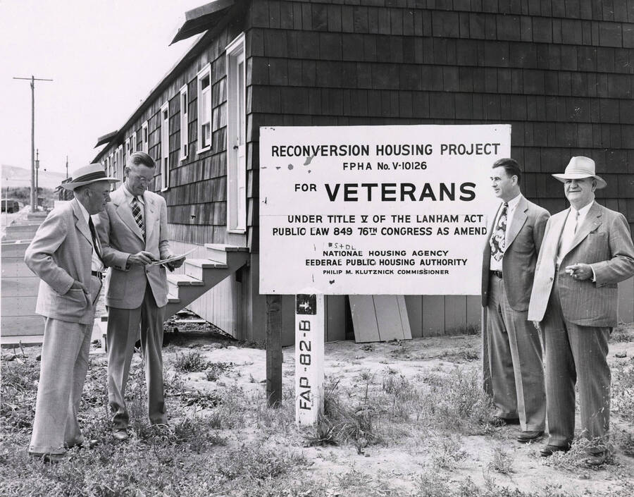 1947 photograph of Veterans Housing on North Main. A group of men stand next to a sign. [PG1_120-01]