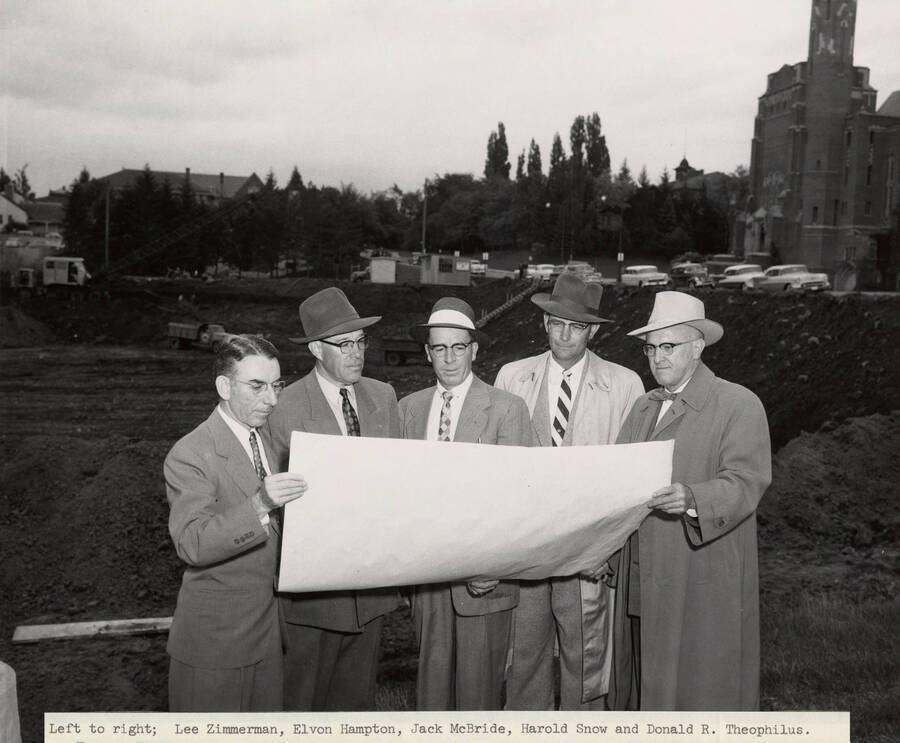 May 26, 1956 photograph of the Library under construction. Left to right: Lee Zimmerman, Elvon Hampton, Jack McBride, Harold Snow, Donald R.Theophilus look over architect's plans. [PG1_122-078a]