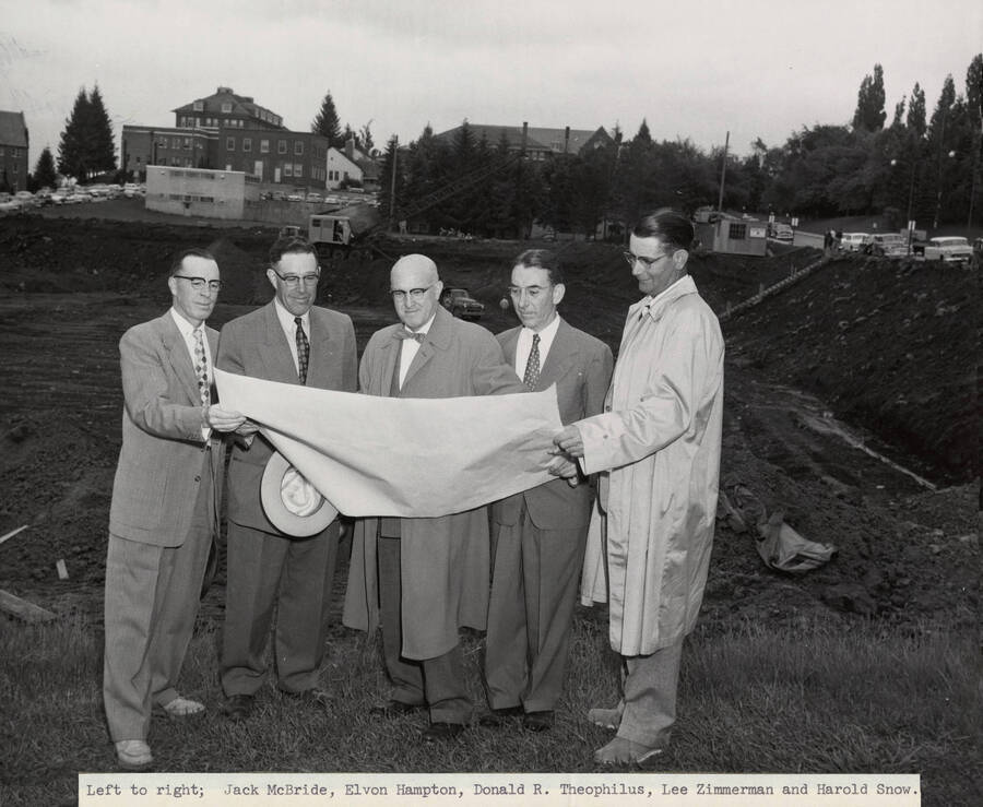 May 24, 1956 photograph of the Library under construction. Left to right: Jack McBride, Elvon Hampton, Donald R.Theophilus, Lee Zimmerman, Harold Snow look over an architect's plans. [PG1_122-078b]
