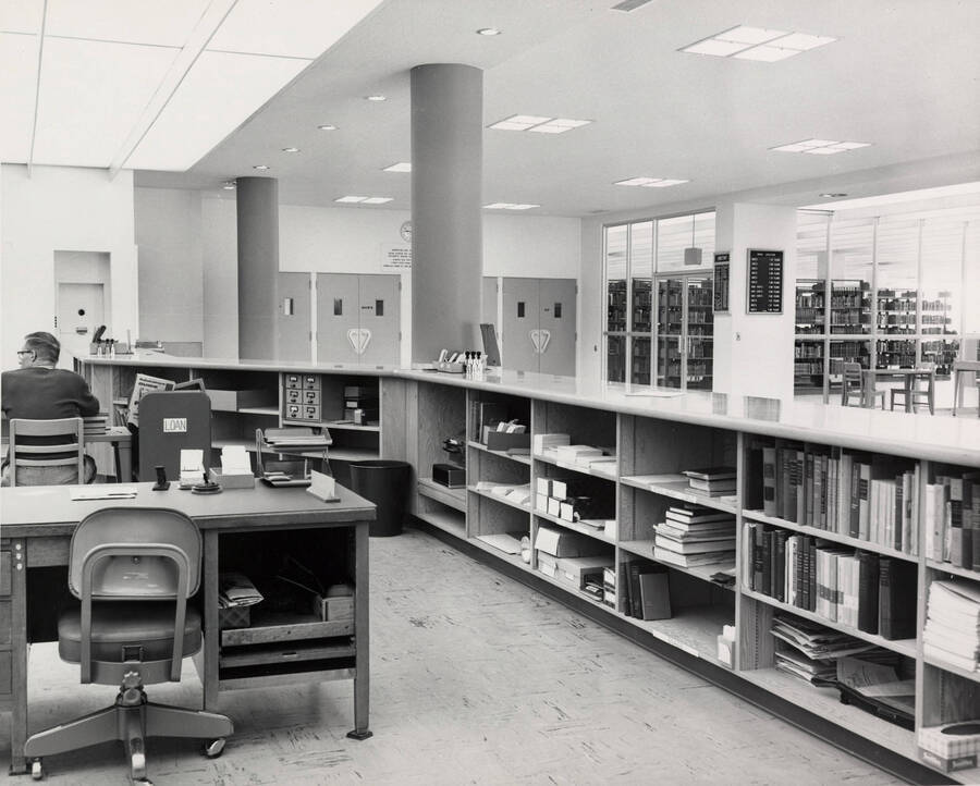 1957 photograph of the Library. A library employee sits to the left. [PG1_122-019]