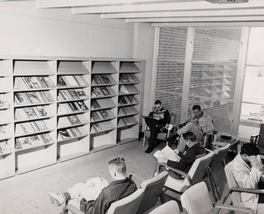 1957 photograph of the Library. Students read newspapers and magazines in foreground. [PG1_122-022]