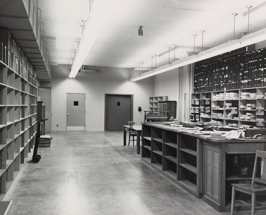 1957 photograph of the Library. Shipping and receiving area with shelves to the left and right. [PG1_122-035]