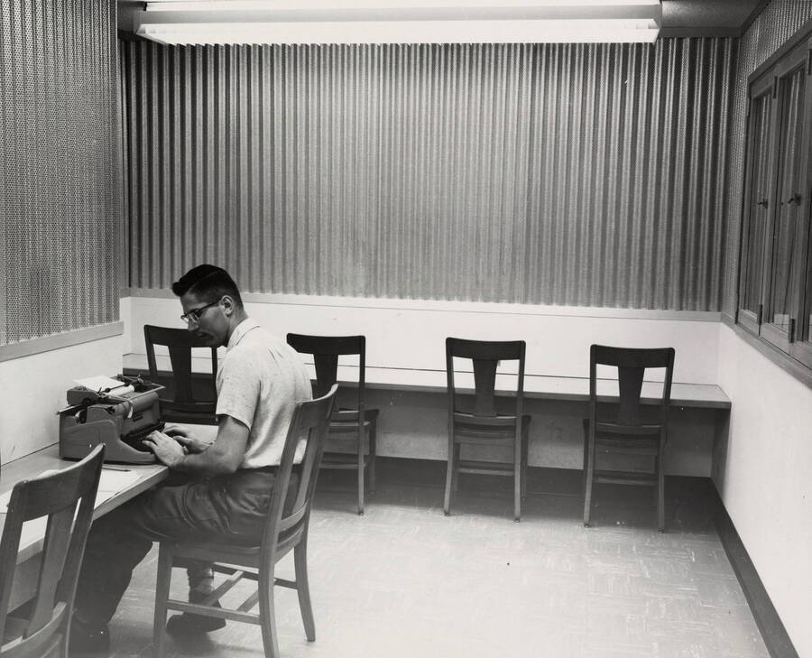 1957 photograph of the Library. A student works in the typing room. [PG1_122-039]