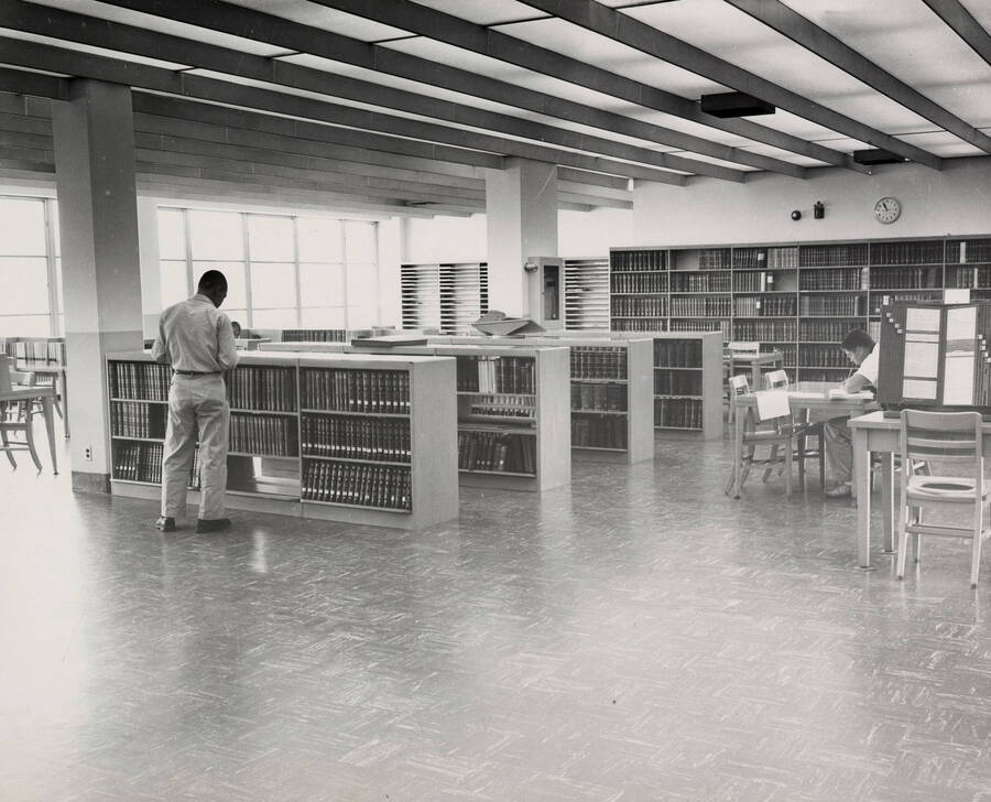 1957 photograph of the Library. Students are seen browsing books and studying. [PG1_122-004]