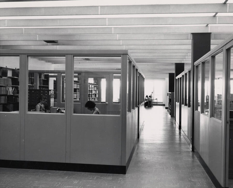 1957 photograph of the Library. Library employee offices with students in background. [PG1_122-058]