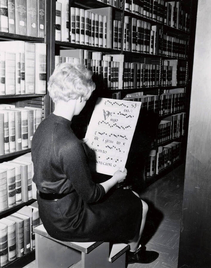 1957 photograph of the Library. Student studies medieval sheet music in Special Collections stacks. Donor: Publications Dept. [PG1_122-075]