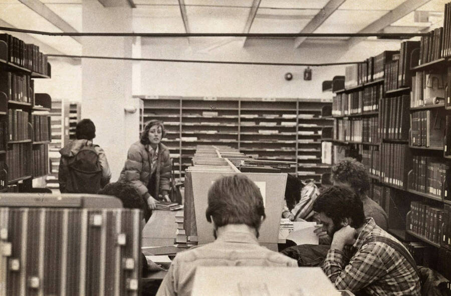 1978 photograph of the Library. Students study near the periodical shelves. [PG1_122-086]