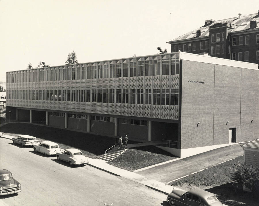 1962 photograph of the Mines Building. Students and automobiles in foreground, Morill Hall in background. [PG1_125-13]