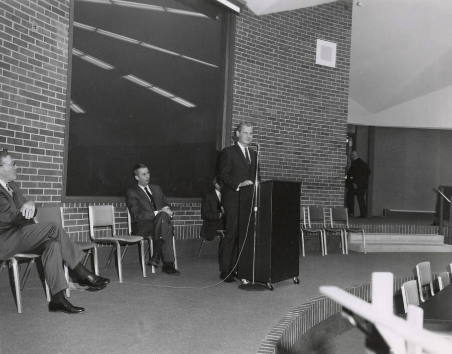 1969 photograph of the Education Building dedication ceremony. Man speaking in Kiva. Donor: Publications Dept. [PG1_139-06]