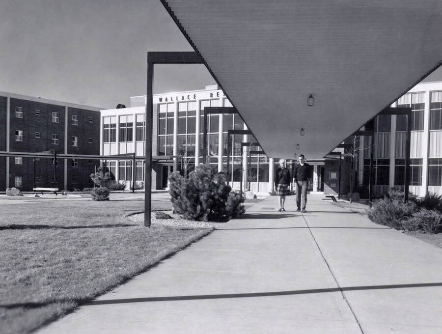 1965 photograph of the Wallace Residence Center. Two students walk away from entrance. [PG1_141-10]