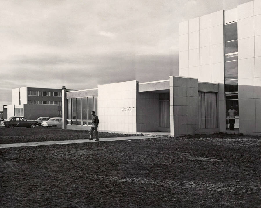 1957 photograph of the William J. McConnell Residence Hall. Student in foreground, automobiles in background. Donor: Publications Dept. [PG1_142-03]