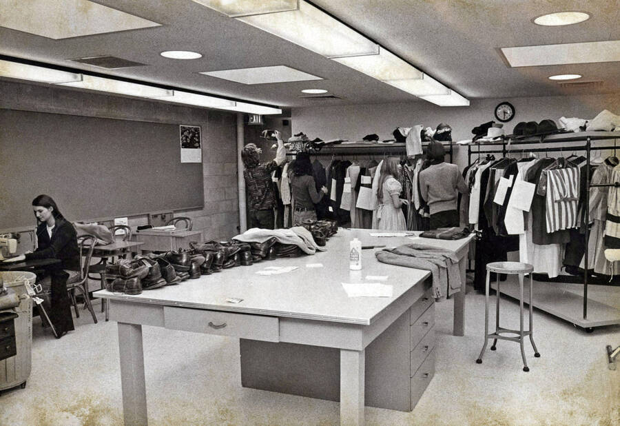1974 photograph of the Hartung Theatre. Students examine costumes in the costume storage room. [PG1_145-12]
