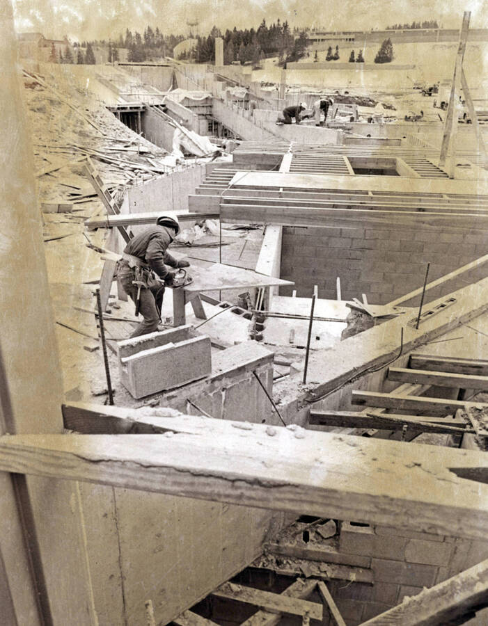 1974 photograph of the Hartung Theatre under construction. Construction worker in foreground. [PG1_145-03]