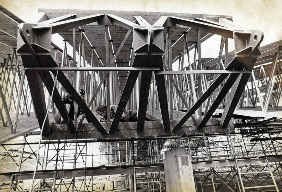 1975 photograph of the Kibbie-ASUI Activity Center under construction. Construction workers in foreground. [PG1_147-15]