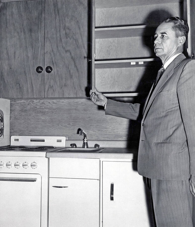 1957 photograph of the Park Village Apartments. Warner Cornish Jr., Director of Family Housing inspects a kitchen. Donor: Publications Dept. [PG1_154-03]