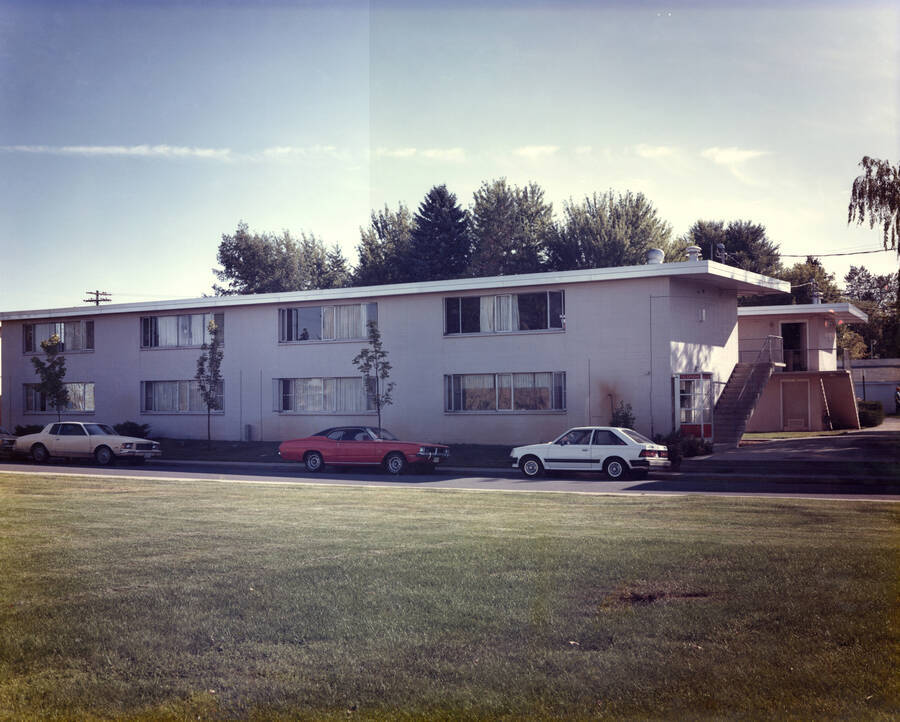 1985 photograph of the Park Village Apartments. Automobiles in foreground.. Donor: Facilities Planning. [PG1_154-07]