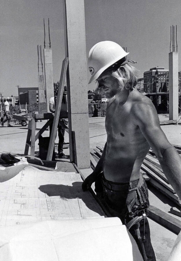 1974 photograph of Menard Law Building under construction. A shirtless man in foreground. [PG1_162-10]