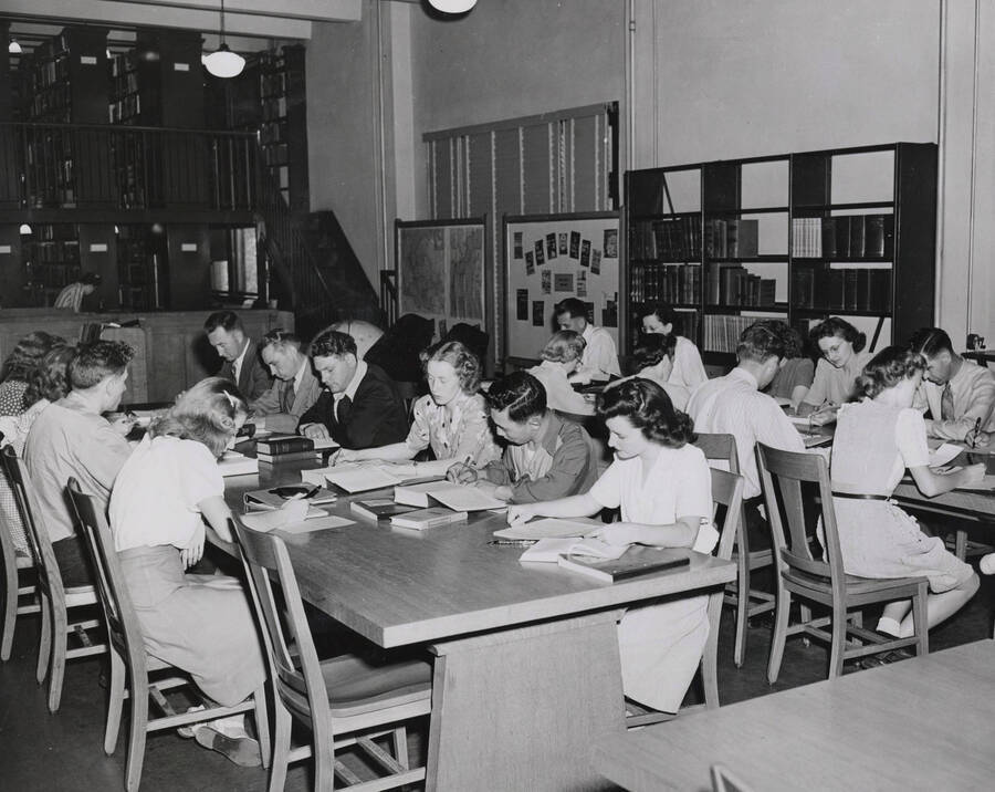 1947 photograph of the Library. Students read in the reading room, stacks in background. [PG1_201-16]