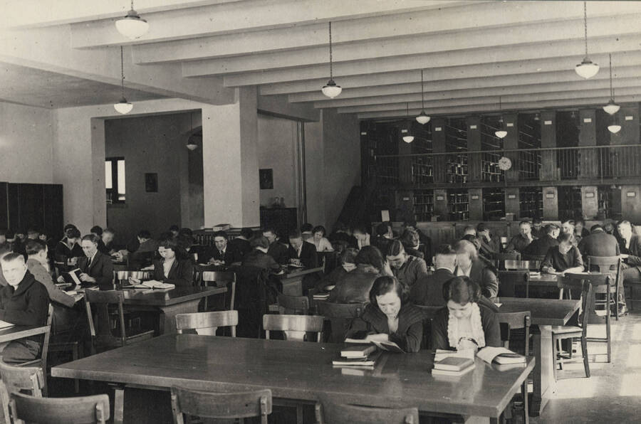 1922 photograph of the Library. Students studying, stacks in background. [PG1_201-03]