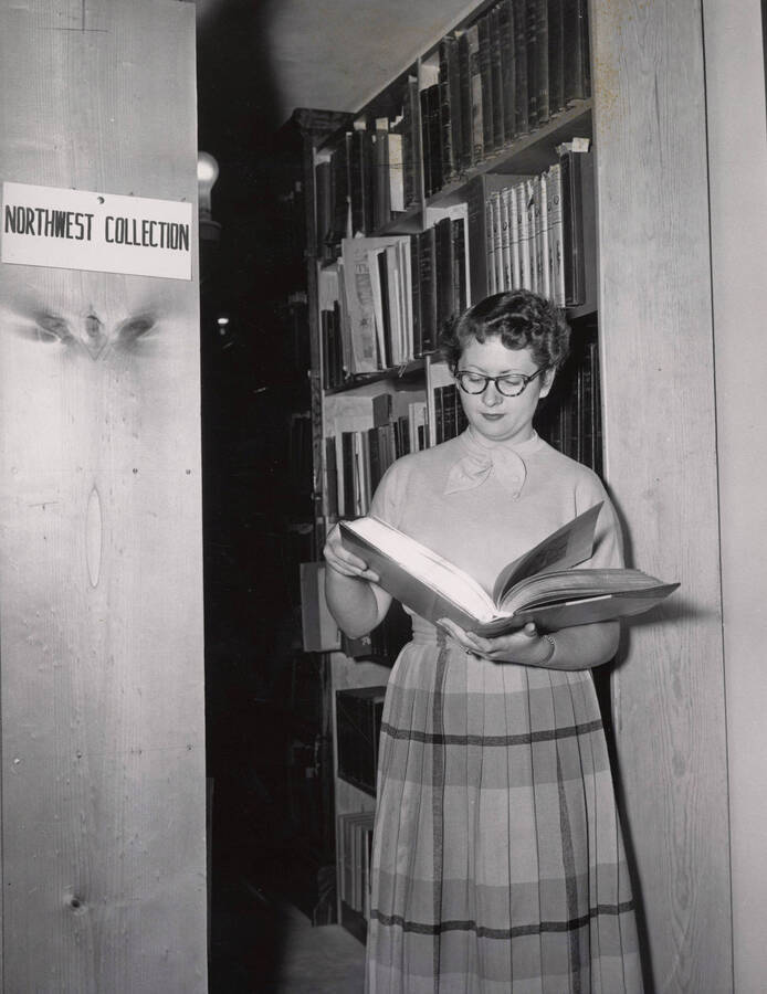 1952 photograph of the Library. A library employee browses a book in the Special Collections area. Donor: Publications Dept. [PG1_201-30]
