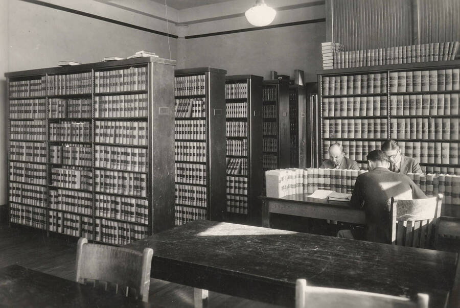 1936 photograph of the Law Library. Students study around stacks of law books. [PG1_202-01]