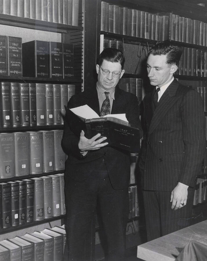 1947 photograph of the Law Library. Two men look through a book. Donor: Publications Dept. [PG1_202-09]