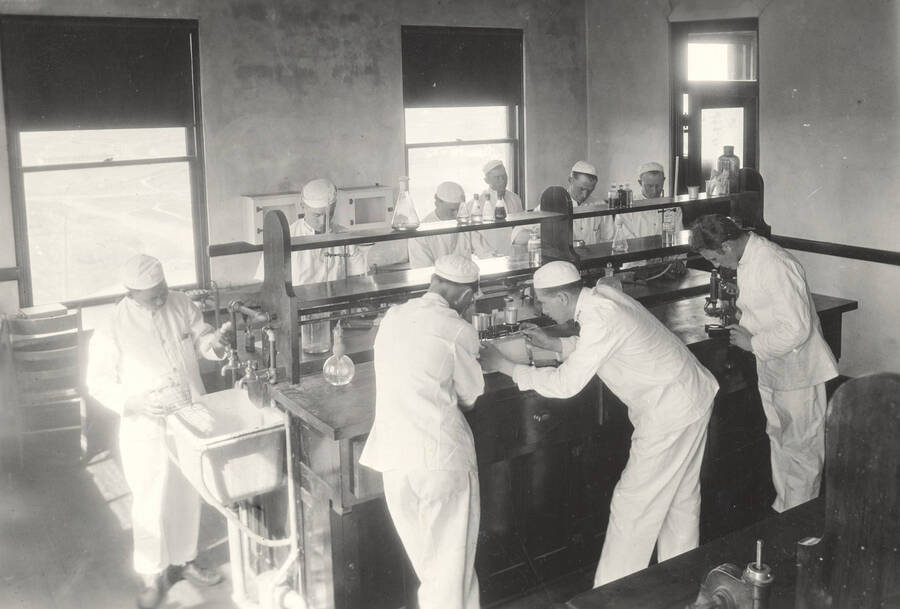 1925 photograph of Dairy Farm and Creamery. Students work at a lab table in the Creamery. [PG1_205-22]