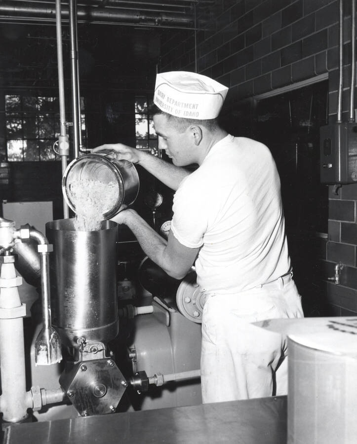 1960 photograph of Dairy Farm and Creamery. A student fills an ice cream machine. Donor: Photo Center. [PG1_205-27]
