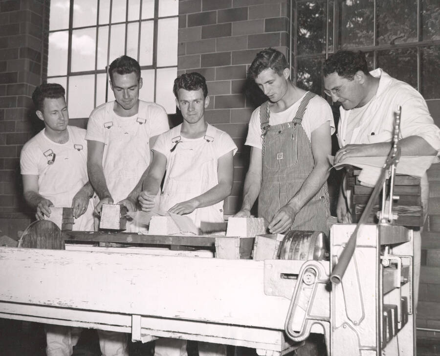 1953 photograph of Dairy Farm and Creamery. Five students examine bricks of freshly made cheese. Donor: Publications Dept. [PG1_205-34c]