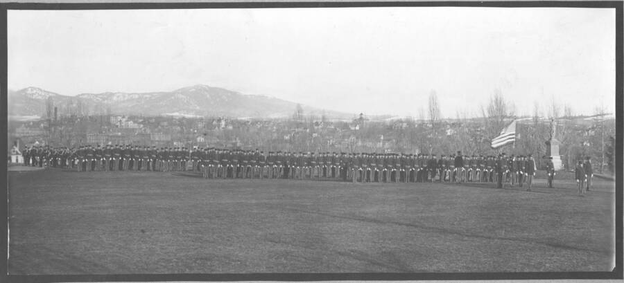1907 photograph of Military Science Cadets. Cadets on parade with campus visible in the background. [PG1_208-112]