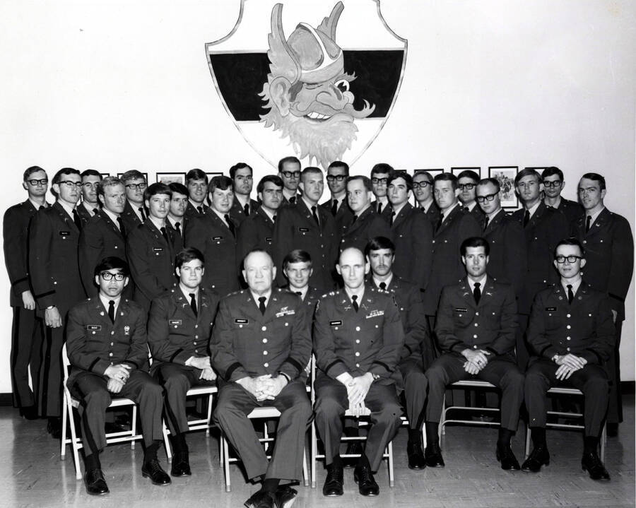 1970-05-31 photograph of Military Science Cadets. Newly commissioned officers in front of an image of Joe Vandal. Donor: Army ROTC. [PG1_208-119]