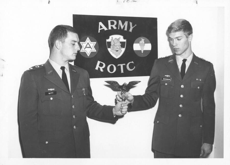 1967 photograph of Military Science Cadets. Cadets Rodney W Bohman and James B. Witt hold an eagle flagpole marker. Donor: Publications Dept. [PG1_208-125]