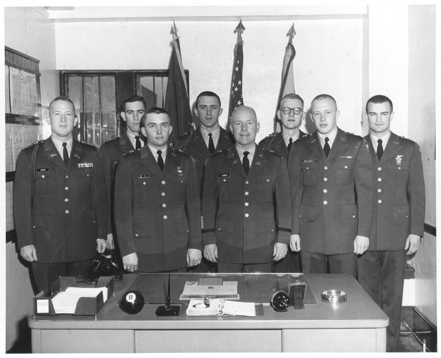 1960 photograph of Military Science Cadets. Department staff behind an office desk. Donor: Publications Dept. [PG1_208-130]