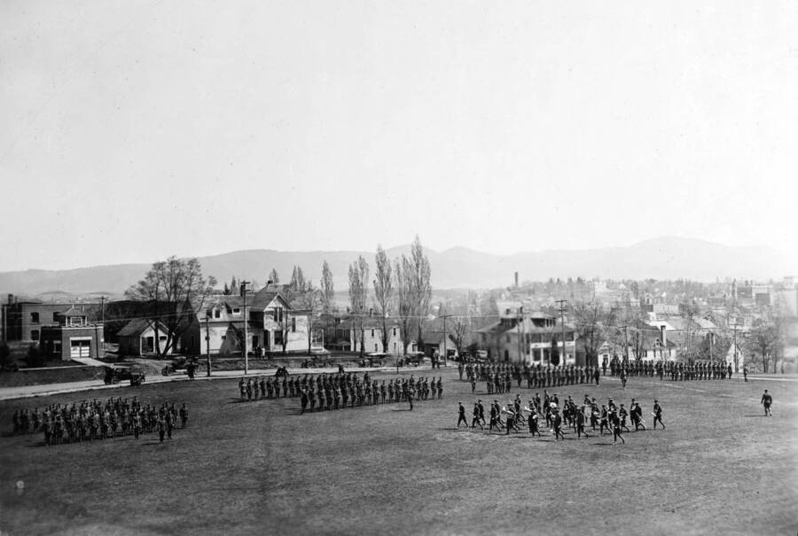 1922 photograph of Military Science Cadets. ROTC battalion in formation in field. University buildings visible in the background. [PG1_208-155]