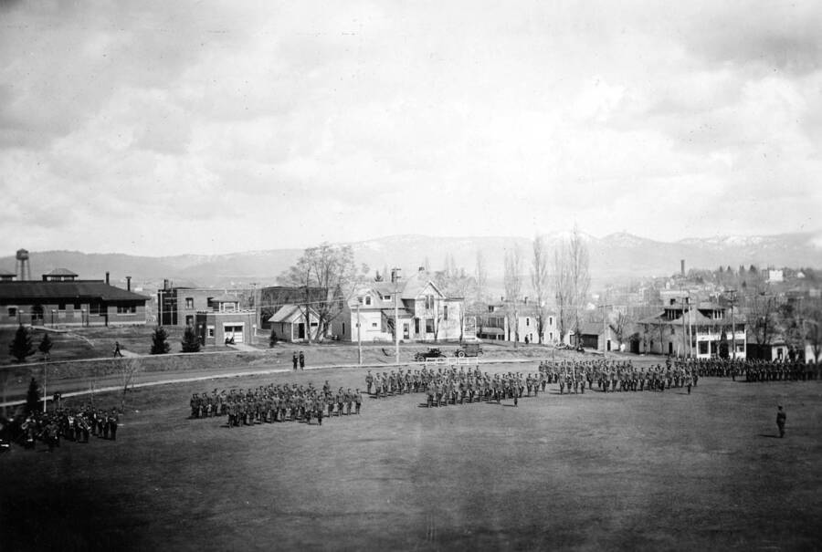 1922 photograph of Military Science Cadets. ROTC battalion in formation in field. University buildings visible in the background. [PG1_208-156]