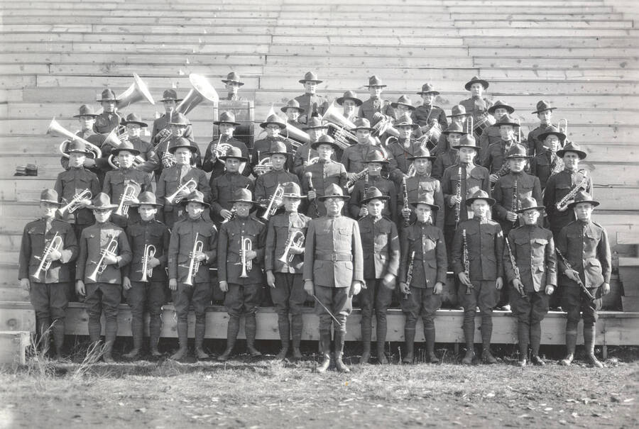 1925 photograph of Military Science Cadets. Military band in formation on campus bleachers. [PG1_208-033]