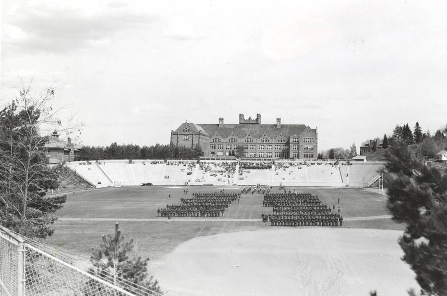 1936 photograph of Military Science Cadets. Military cadets on inspection at MacLean Field. Administration building is visible in the background. [PG1_208-042]